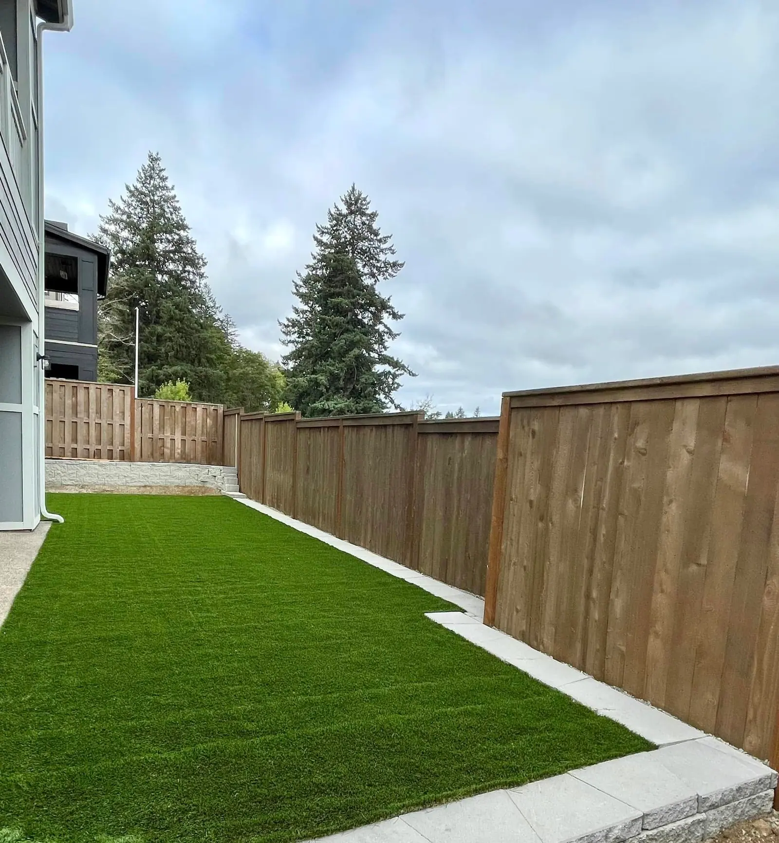 Artificial turf lawn enclosed by a new cedar privacy fence