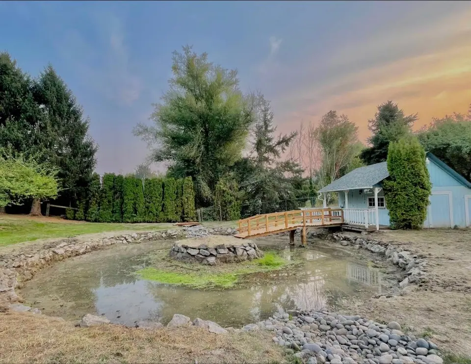 Backyard pond at dusk with rock edging and open lawn