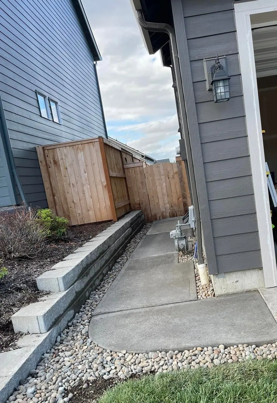 Block retaining wall paired with a new cedar privacy fence and gate