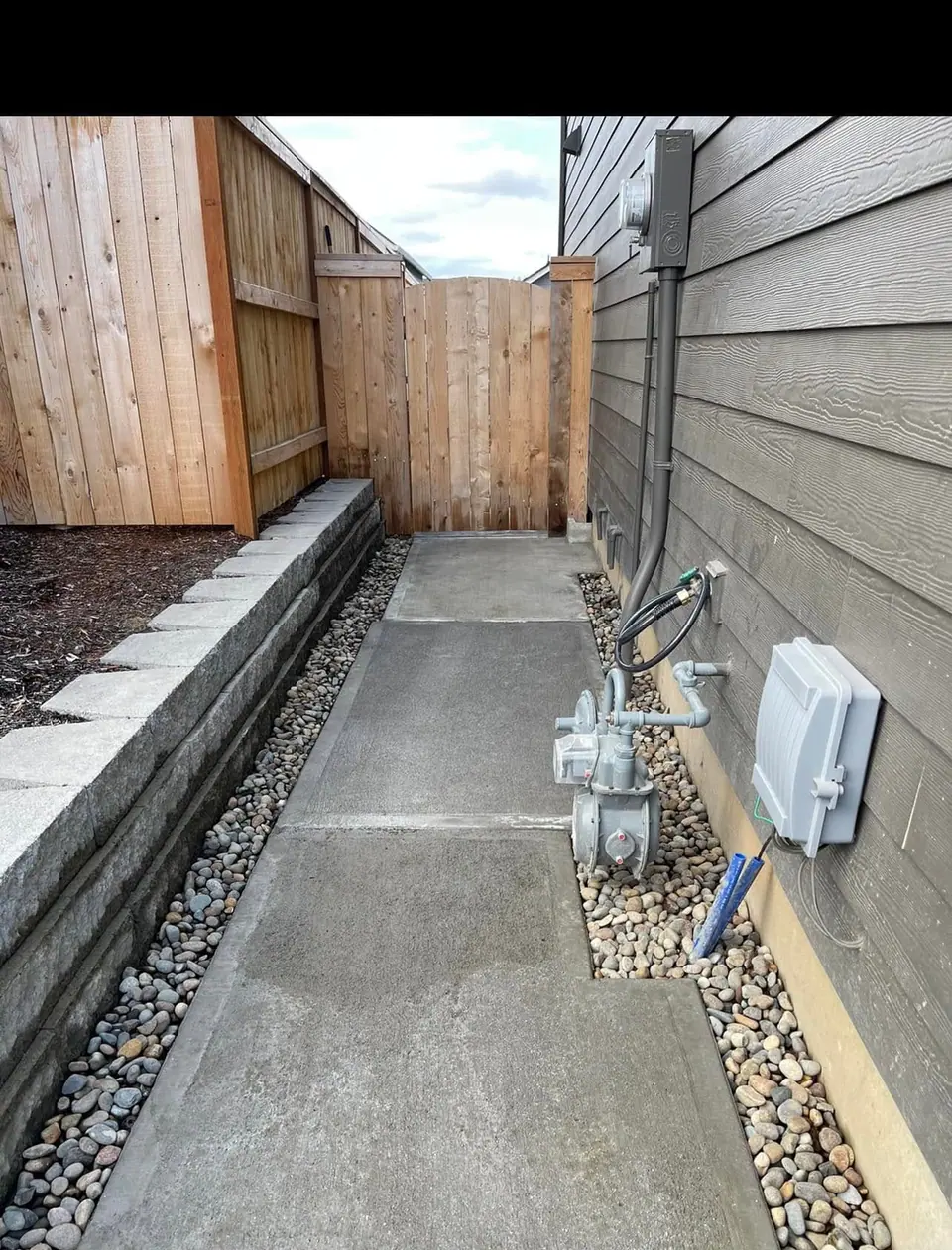Concrete block retaining wall built along a side yard with a gravel drainage strip