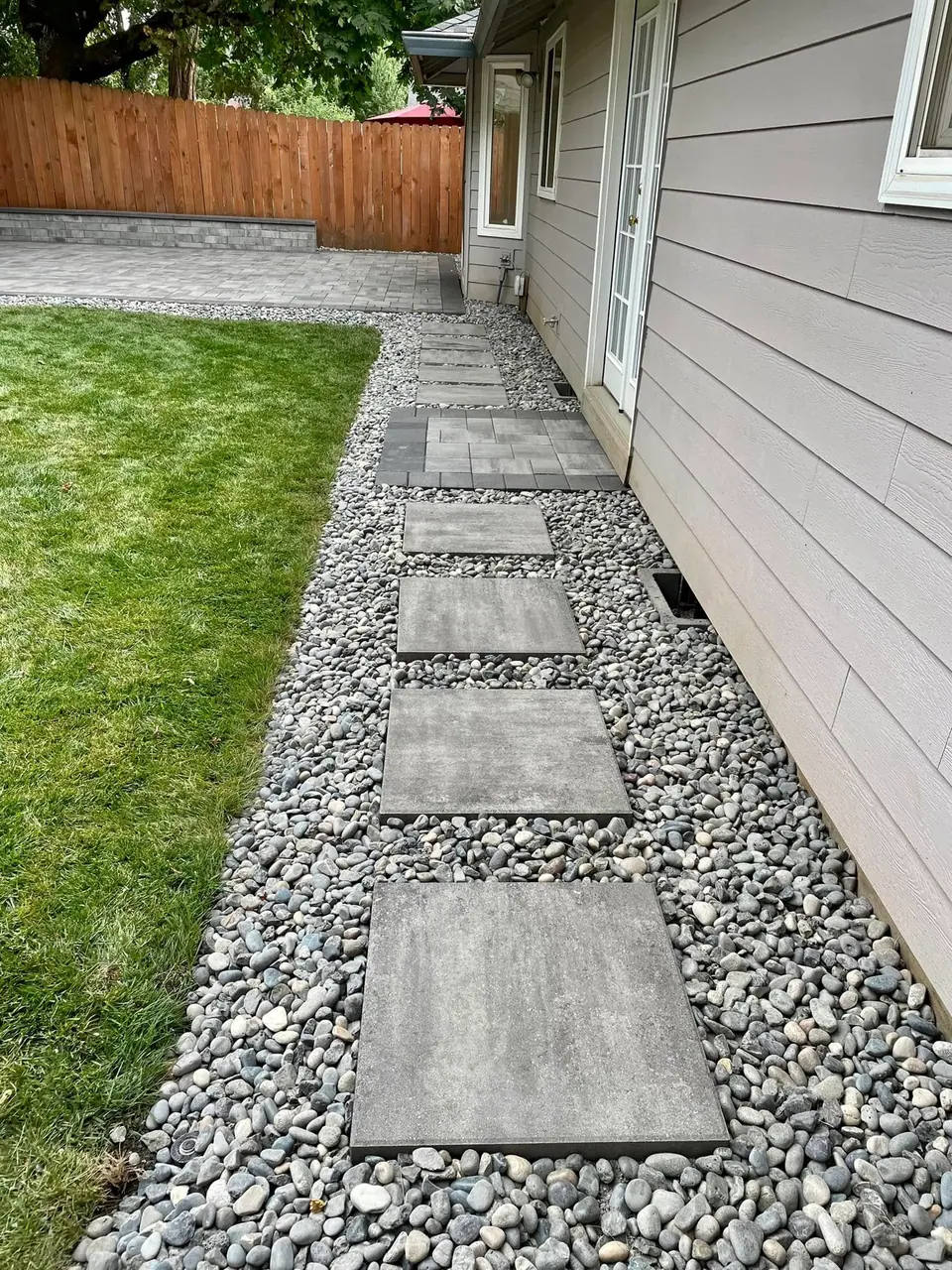 Concrete stepping pads set into a river rock drainage strip