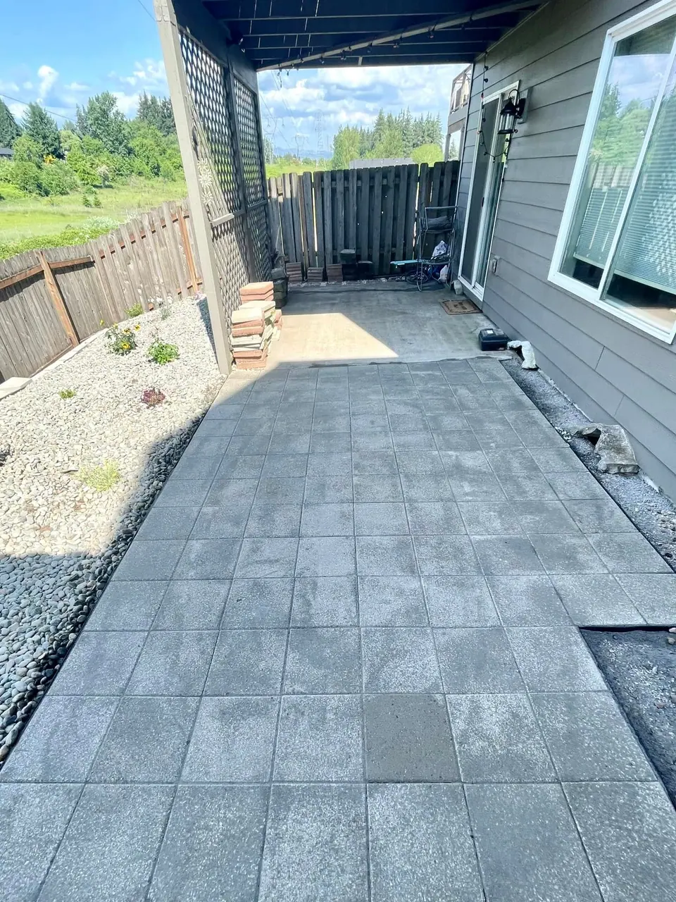 Large paver patio with a decorative gravel border and iron railing