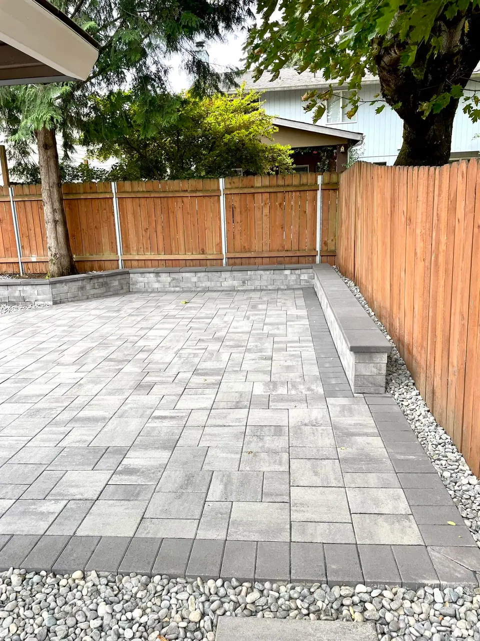 Paver patio with a stone bench tucked against a cedar fence