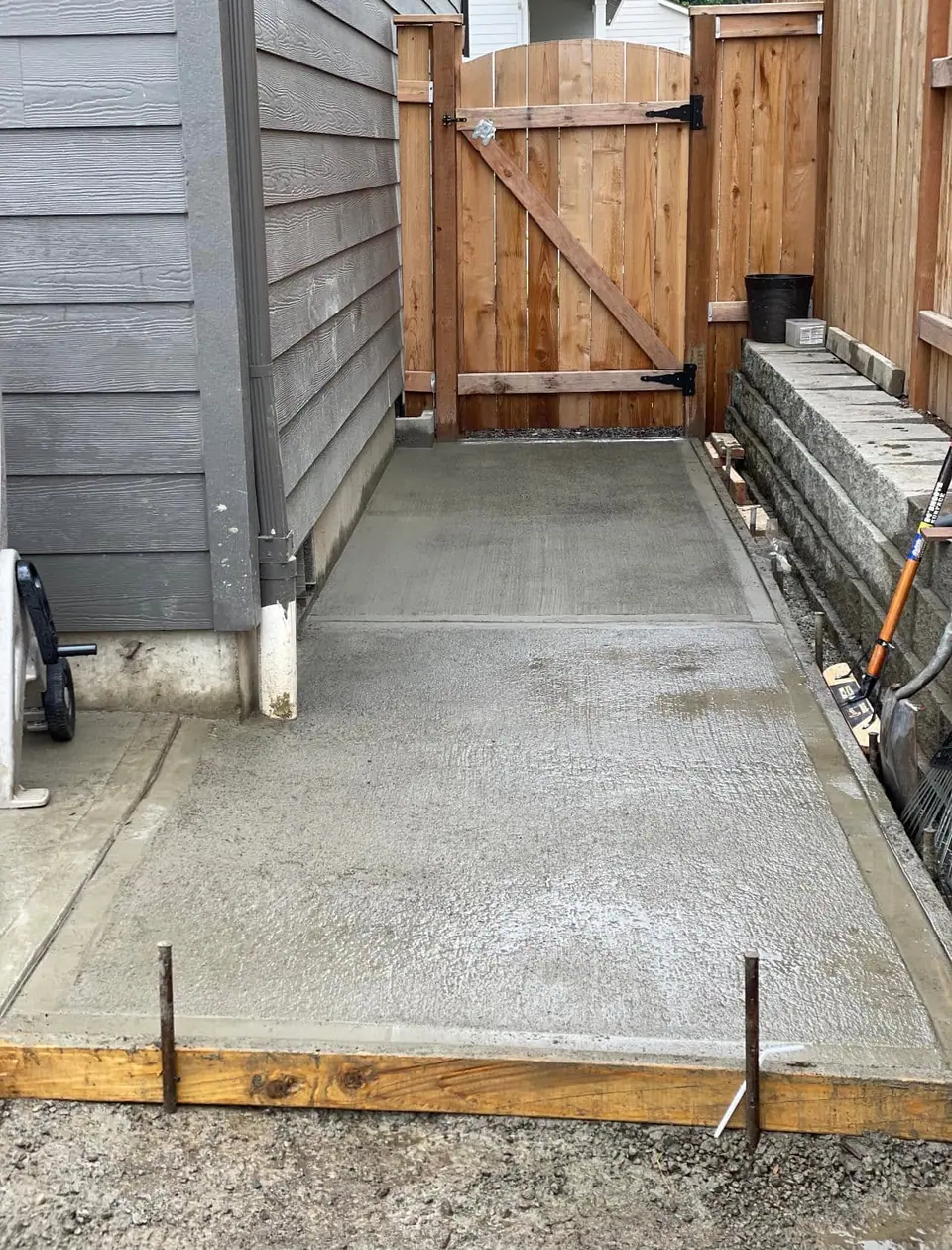 Side yard concrete pad finished against a stacked block retaining wall